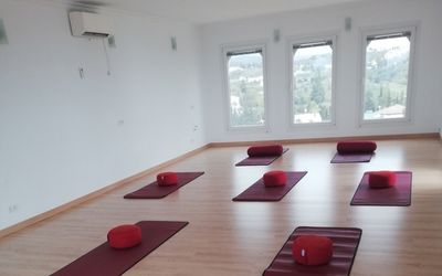 Bright yoga room in Villa Morisco with laid out yoga mats and red meditation cushions for body and mind sessions.