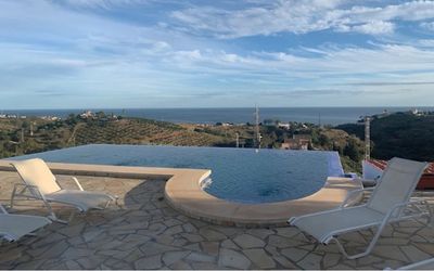 Infinity pool of Villa Morisco in Málaga with white sun loungers and a wide view of the Mediterranean Sea for relaxing.